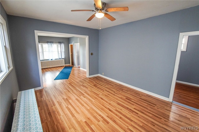 spare room featuring light hardwood / wood-style flooring, radiator heating unit, and ceiling fan