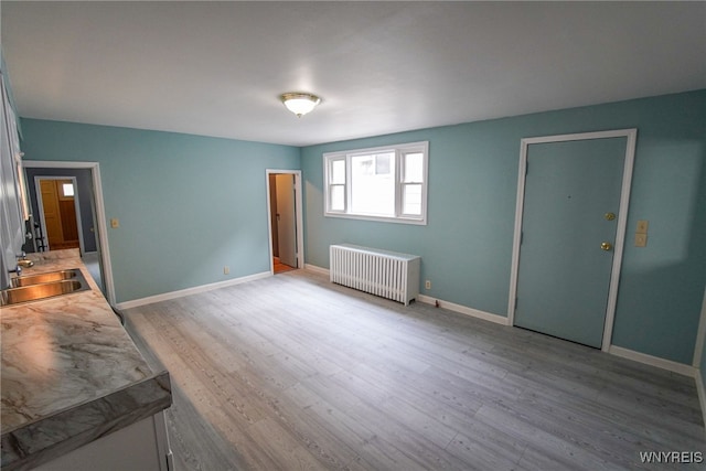 spare room with hardwood / wood-style flooring, radiator heating unit, and sink