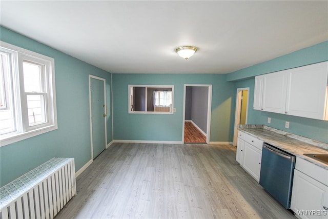 kitchen featuring white cabinets, radiator, stainless steel dishwasher, and a wealth of natural light