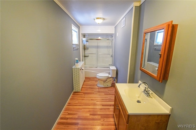 full bathroom with crown molding, vanity, hardwood / wood-style floors, toilet, and combined bath / shower with glass door