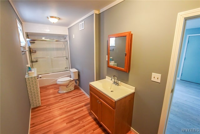 full bathroom featuring ornamental molding, combined bath / shower with glass door, wood-type flooring, vanity, and toilet