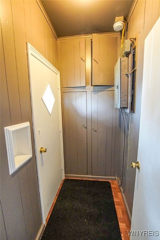 doorway featuring electric panel, wooden walls, and parquet flooring