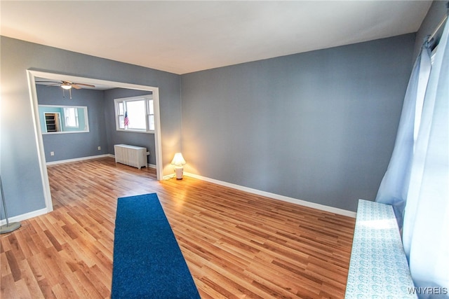 workout area featuring ceiling fan, radiator heating unit, and light hardwood / wood-style floors