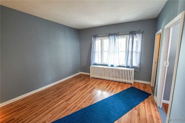 spare room featuring wood-type flooring and radiator heating unit