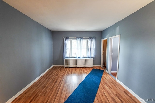 unfurnished room with hardwood / wood-style flooring and radiator heating unit