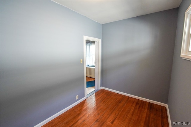 unfurnished room featuring hardwood / wood-style flooring and radiator