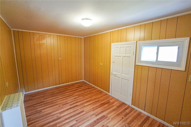 unfurnished bedroom featuring a closet, wooden walls, and light hardwood / wood-style floors