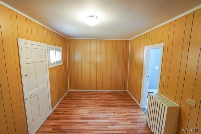 interior space featuring wooden walls, ornamental molding, and light hardwood / wood-style flooring