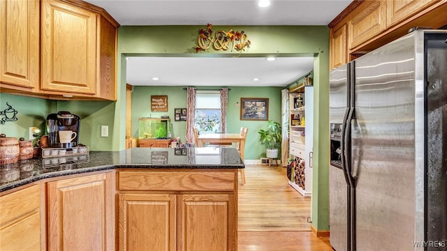 kitchen featuring dark stone counters, kitchen peninsula, stainless steel fridge with ice dispenser, and light hardwood / wood-style floors