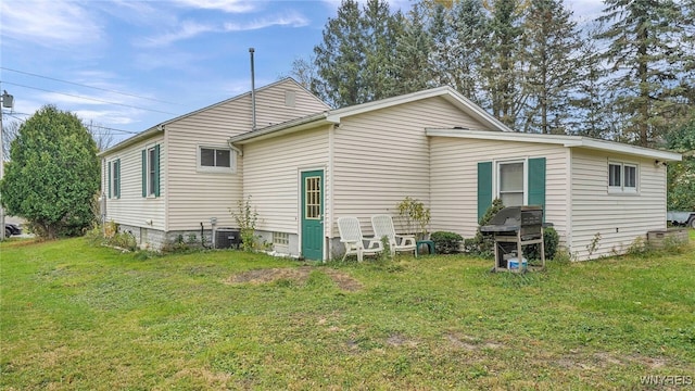 rear view of property with central AC unit and a yard