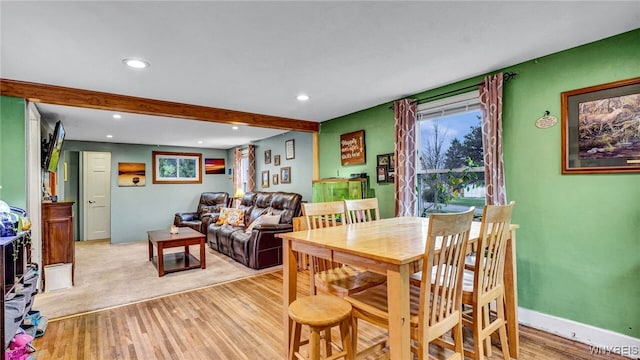 dining space with beamed ceiling and light hardwood / wood-style flooring