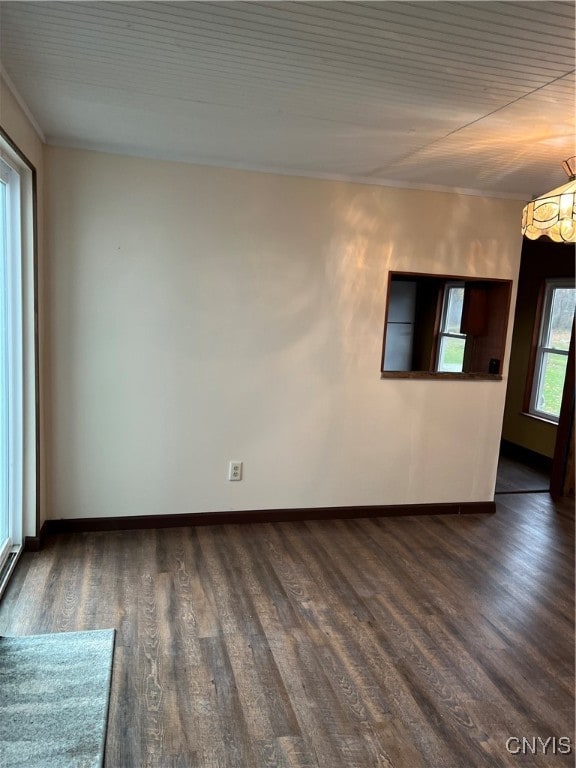 empty room with crown molding, dark hardwood / wood-style flooring, and a notable chandelier