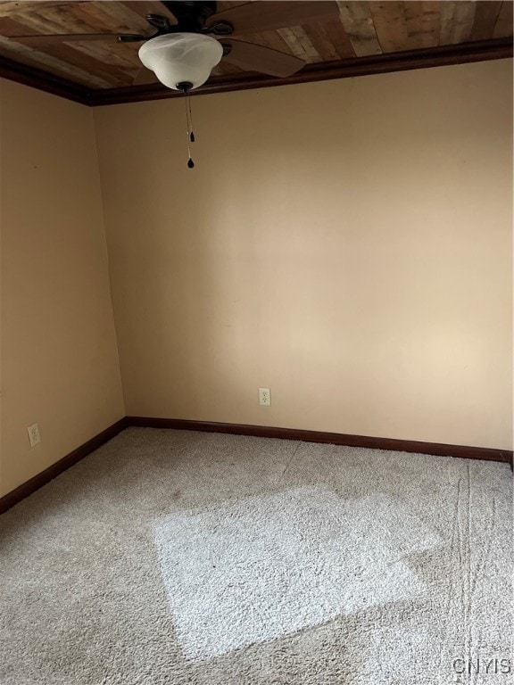 carpeted empty room featuring ornamental molding, ceiling fan, and wood ceiling