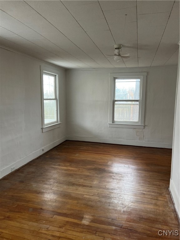 spare room featuring dark wood-type flooring, ceiling fan, and plenty of natural light