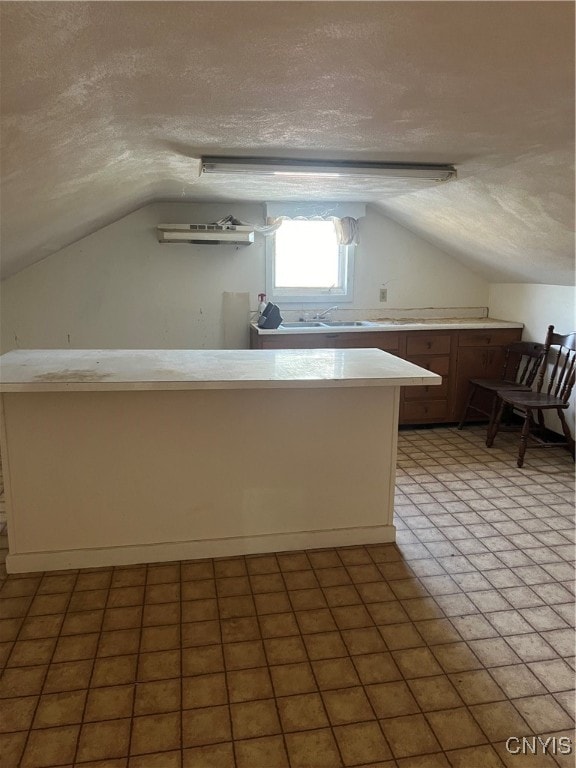 kitchen with kitchen peninsula, lofted ceiling, a textured ceiling, and tile patterned floors