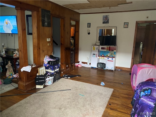 living room with dark hardwood / wood-style flooring, wood walls, and crown molding