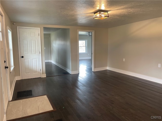 unfurnished room with a textured ceiling and dark hardwood / wood-style floors