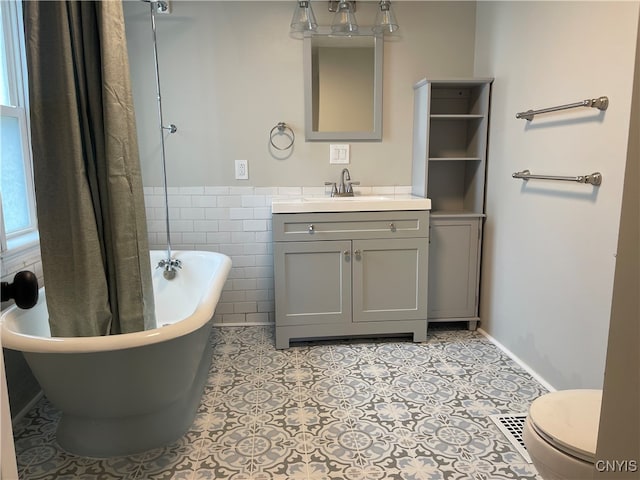 bathroom featuring toilet, a washtub, vanity, and tile patterned floors