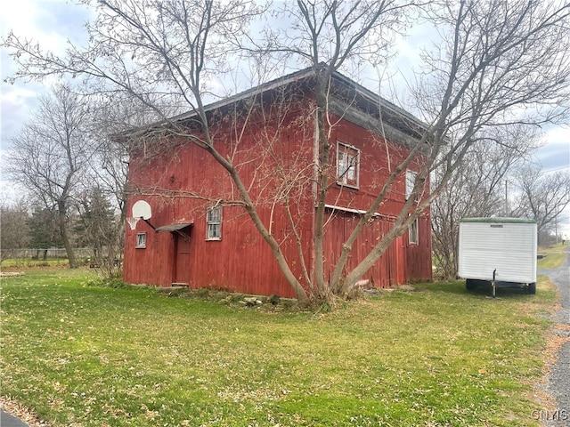 view of side of property featuring a lawn and an outdoor structure