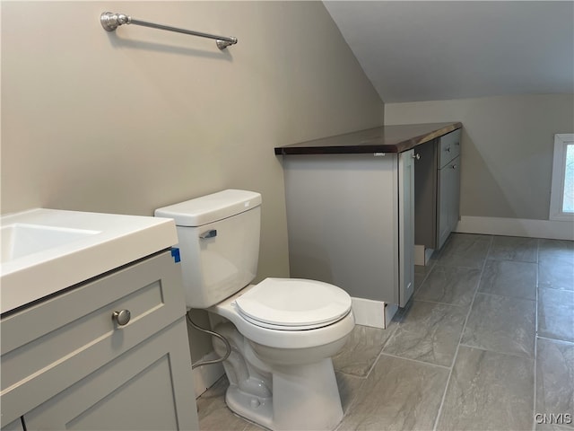 bathroom featuring vanity, toilet, and lofted ceiling