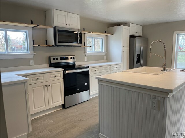 kitchen with plenty of natural light, white cabinetry, and appliances with stainless steel finishes