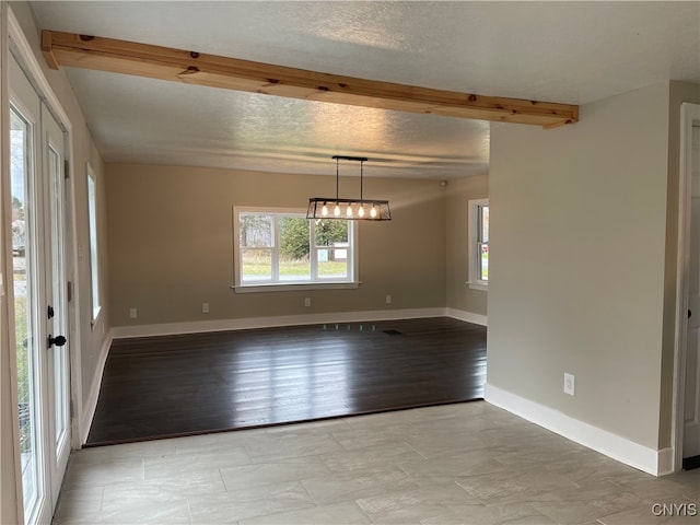 empty room with beamed ceiling, a textured ceiling, and light hardwood / wood-style floors