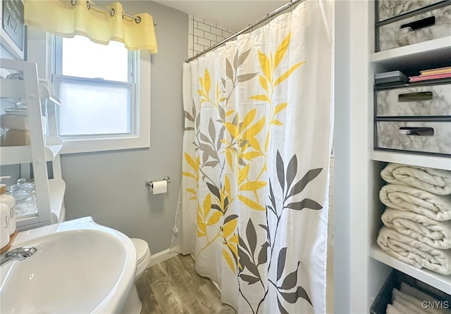 bathroom featuring walk in shower, wood-type flooring, sink, and toilet