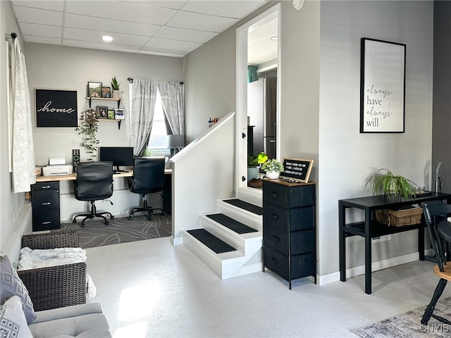 office area with a drop ceiling and concrete floors