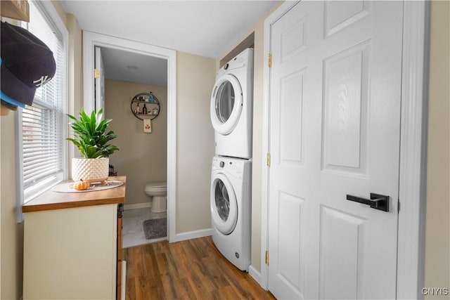 clothes washing area featuring dark hardwood / wood-style floors and stacked washing maching and dryer