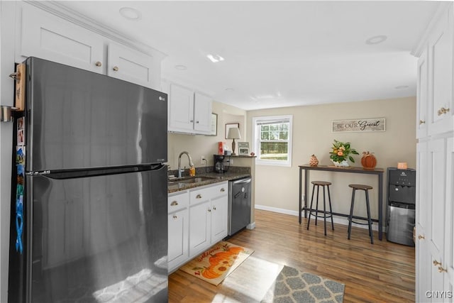 kitchen featuring sink, white cabinetry, dark stone countertops, stainless steel appliances, and dark hardwood / wood-style flooring