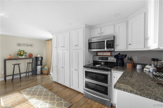 kitchen featuring dark stone countertops, stainless steel appliances, dark hardwood / wood-style floors, and white cabinets