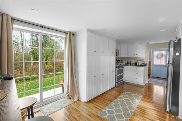 kitchen featuring stainless steel appliances, light hardwood / wood-style floors, and white cabinets