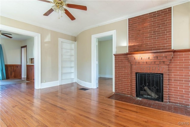 unfurnished living room featuring a fireplace, light hardwood / wood-style floors, built in features, and crown molding