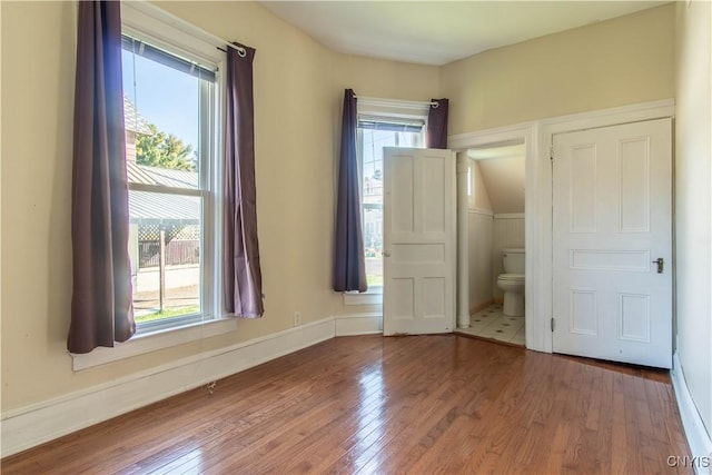 unfurnished bedroom with wood-type flooring and connected bathroom