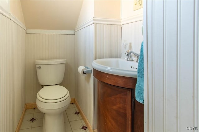 bathroom featuring tile patterned flooring, vanity, toilet, and lofted ceiling