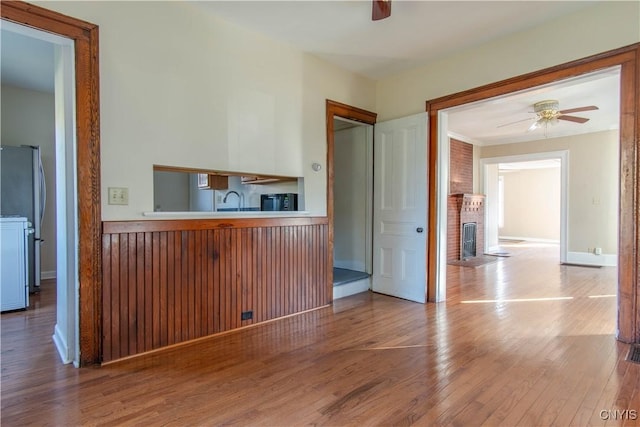 interior space featuring ceiling fan, sink, a fireplace, and light hardwood / wood-style flooring