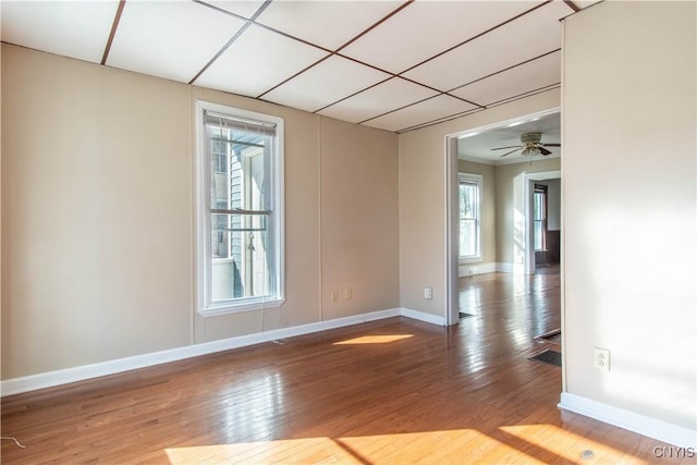 unfurnished room with ceiling fan, a drop ceiling, and wood-type flooring