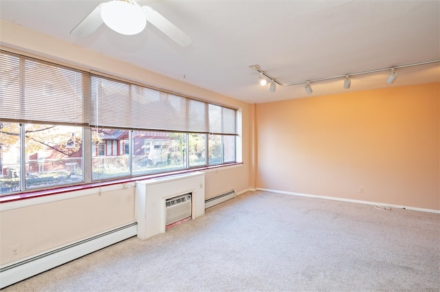 carpeted empty room with an AC wall unit, rail lighting, ceiling fan, and a baseboard radiator