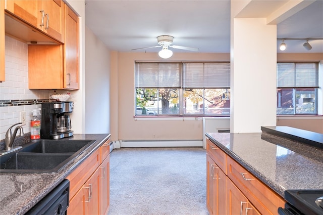 kitchen with black appliances, backsplash, sink, a baseboard heating unit, and dark stone countertops