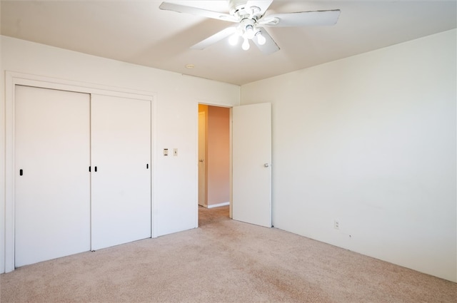 unfurnished bedroom featuring ceiling fan, a closet, and light colored carpet