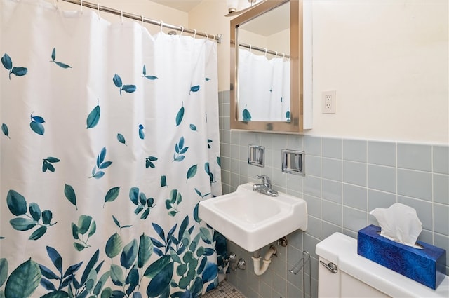 bathroom featuring toilet, tile walls, sink, and curtained shower