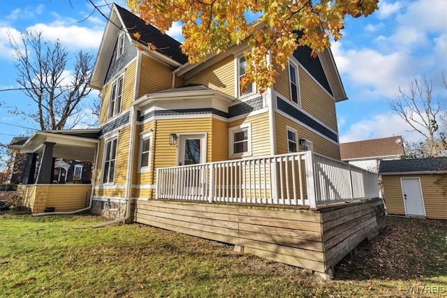 rear view of house featuring a deck, a storage unit, and a yard