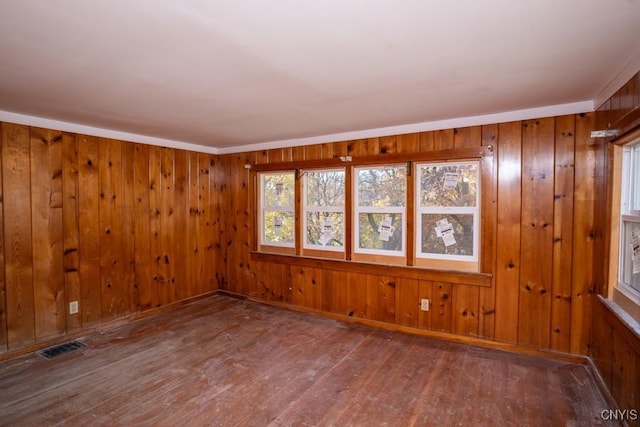 spare room with hardwood / wood-style flooring and wooden walls