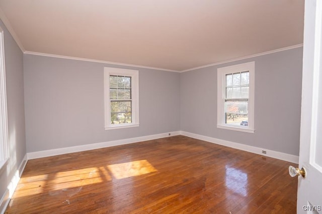 empty room featuring hardwood / wood-style flooring, ornamental molding, and a healthy amount of sunlight