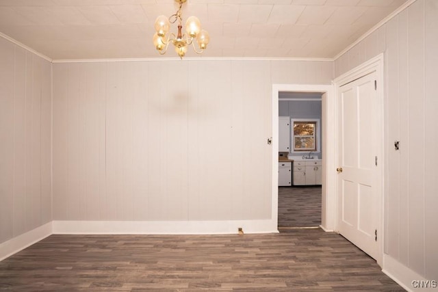 spare room with dark hardwood / wood-style flooring, a notable chandelier, ornamental molding, and sink