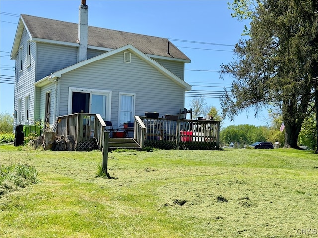 back of property with a wooden deck and a lawn