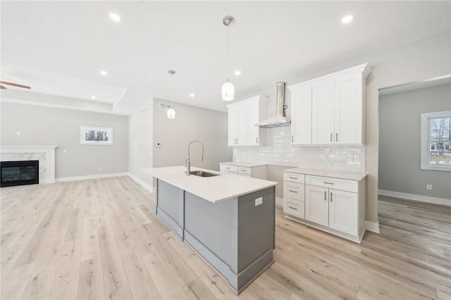 kitchen with ceiling fan, sink, white cabinetry, hanging light fixtures, and wall chimney exhaust hood