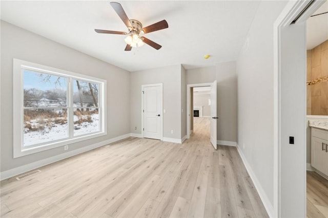 unfurnished bedroom with ceiling fan, light wood-type flooring, and ensuite bathroom