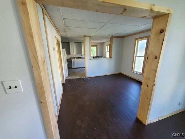 spare room with dark hardwood / wood-style floors, plenty of natural light, sink, and a drop ceiling