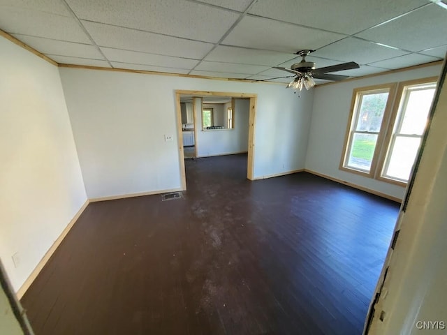 empty room with a paneled ceiling, dark hardwood / wood-style floors, and ceiling fan